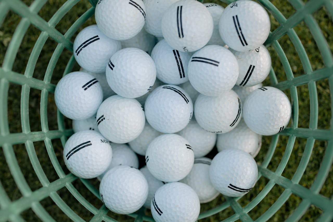 hero-img-01 A high-angle view of golf balls in a basket on grass, illustrating golfing equipment.