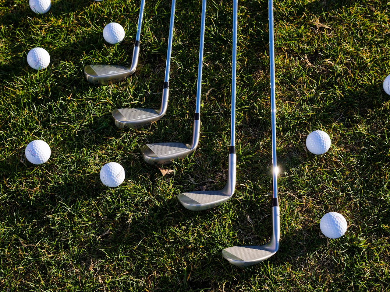 hero-img-02 Flat lay of golf clubs and balls arranged on green grass, perfect for sports enthusiasts.