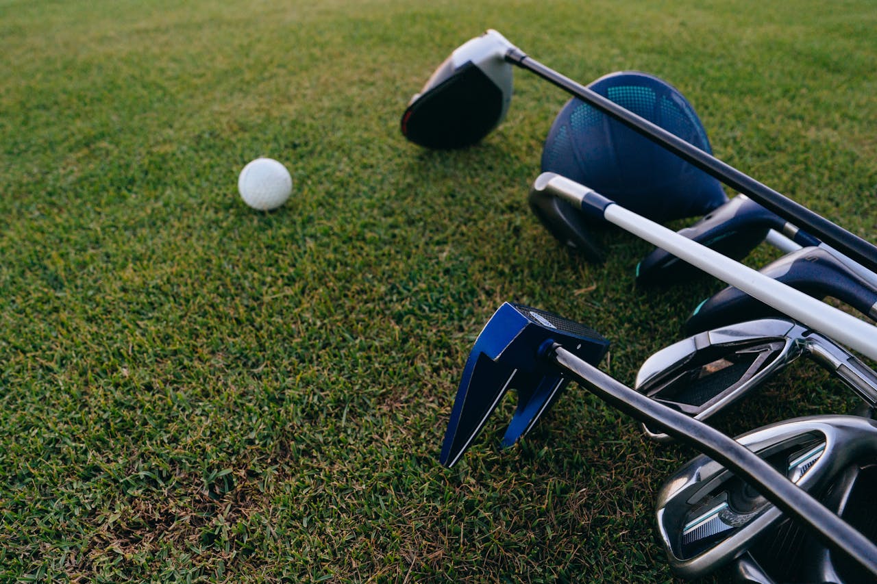 ours-journey A close-up view of golf clubs and a golf ball on a lush green grass field.
